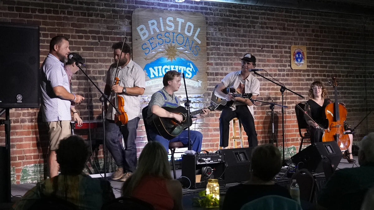The ensemble shares a laugh on stage as a guest speaks at the mic at Bristol Sessions Nights: The Blue Yodel, Bristol Listening Room, L.C. King Building, Bristol, Tennessee