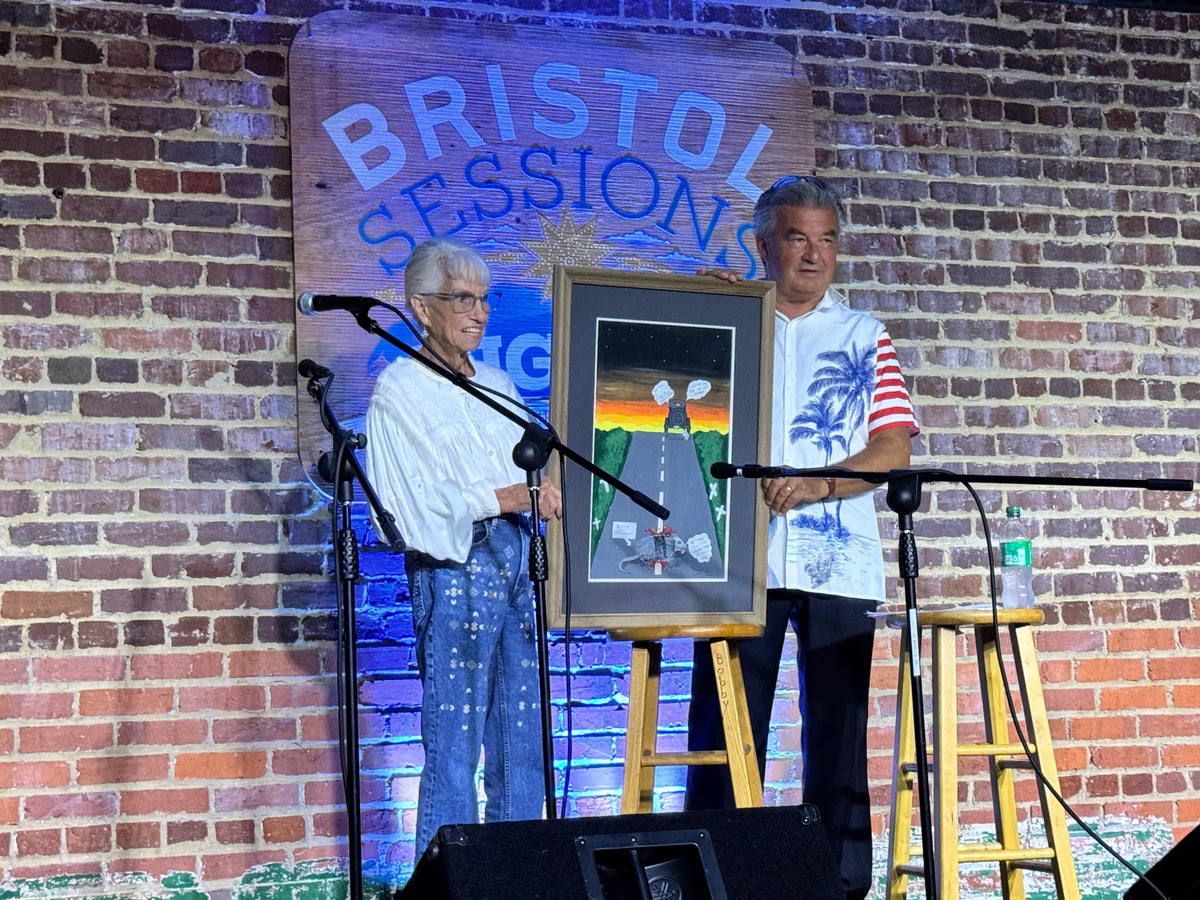 Tim White and a guest stand beside a framed painting presented on stage at Bristol Sessions Nights: Mountain Songs, Bristol Listening Room, L.C. King Building, Bristol, Tennessee