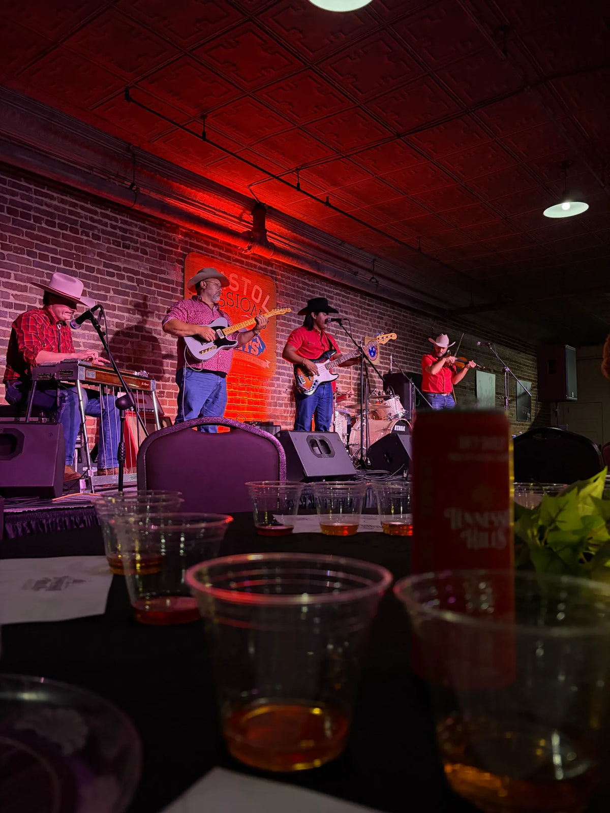Whiskey pours in the foreground as a country band plays on stage at Bristol Sessions Nights: A True Taste of Tennessee, Bristol Listening Room, L.C. King Building, Bristol, Tennessee